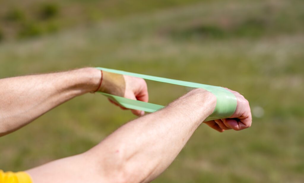 A professional sportsman in is holding a Elastic band expander. He appears focused and determined as he prepares his shoulder and arm muscles for the workout ahead.